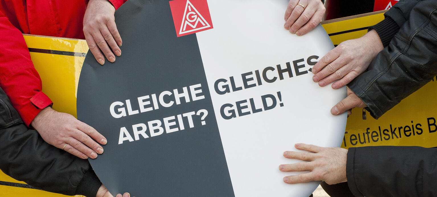 Hände halten Schild 'Gleiche Arbeit? Gleiches Geld!', 