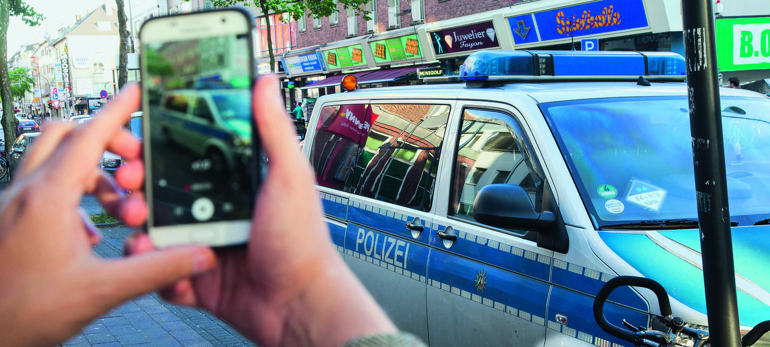 Erlaubt, aber nervig: Ein Bürger filmt Fahrzeuge der Polizei mit dem Smartphone (in Köln).