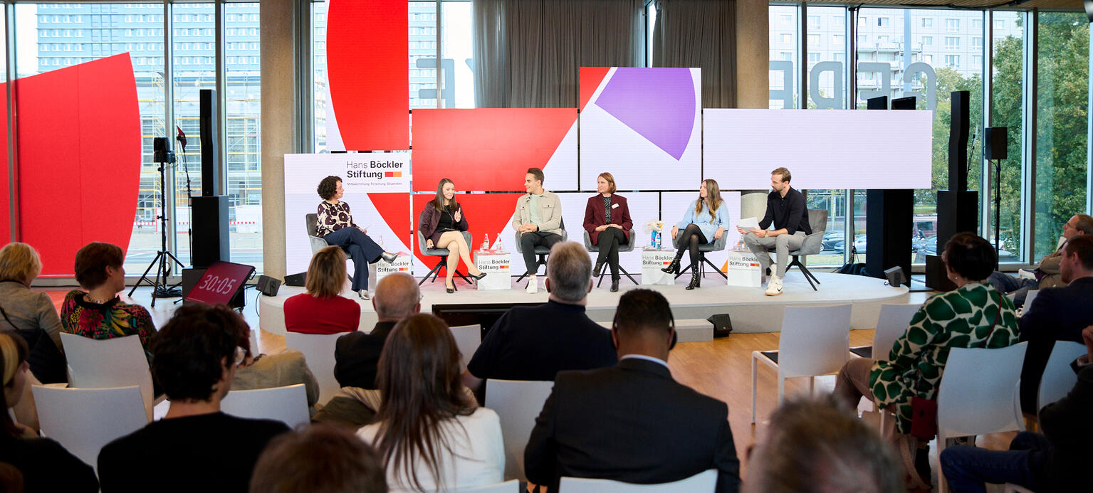 Diskutierende vor Publikum auf Podium