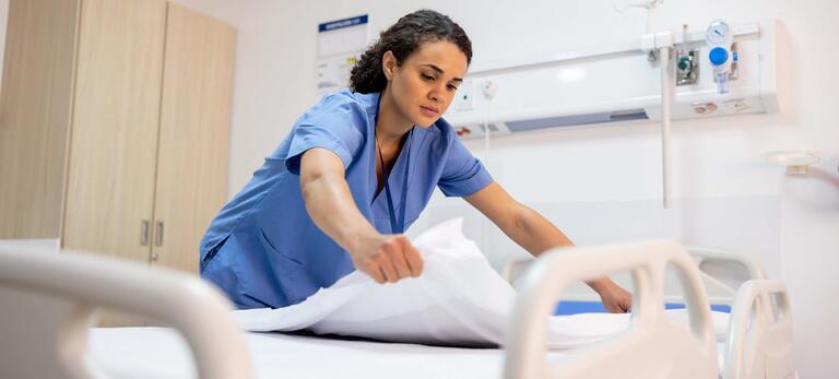 Pflegekraft, die ein Bett herrichtet im Krankenhaus