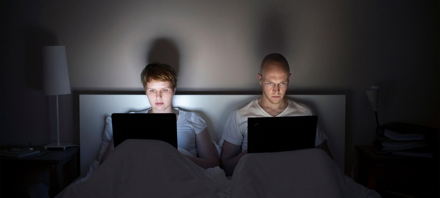 Suchthaftes Arbeiten - Junges Paar arbeitet nachts im Bett mit seinem Laptop