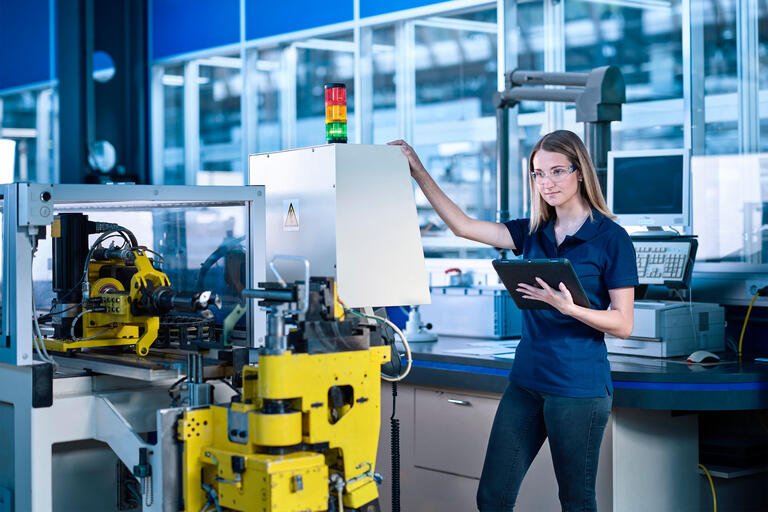 Engineer with tablet PC standing near machine in industry - Arbeitskosten
