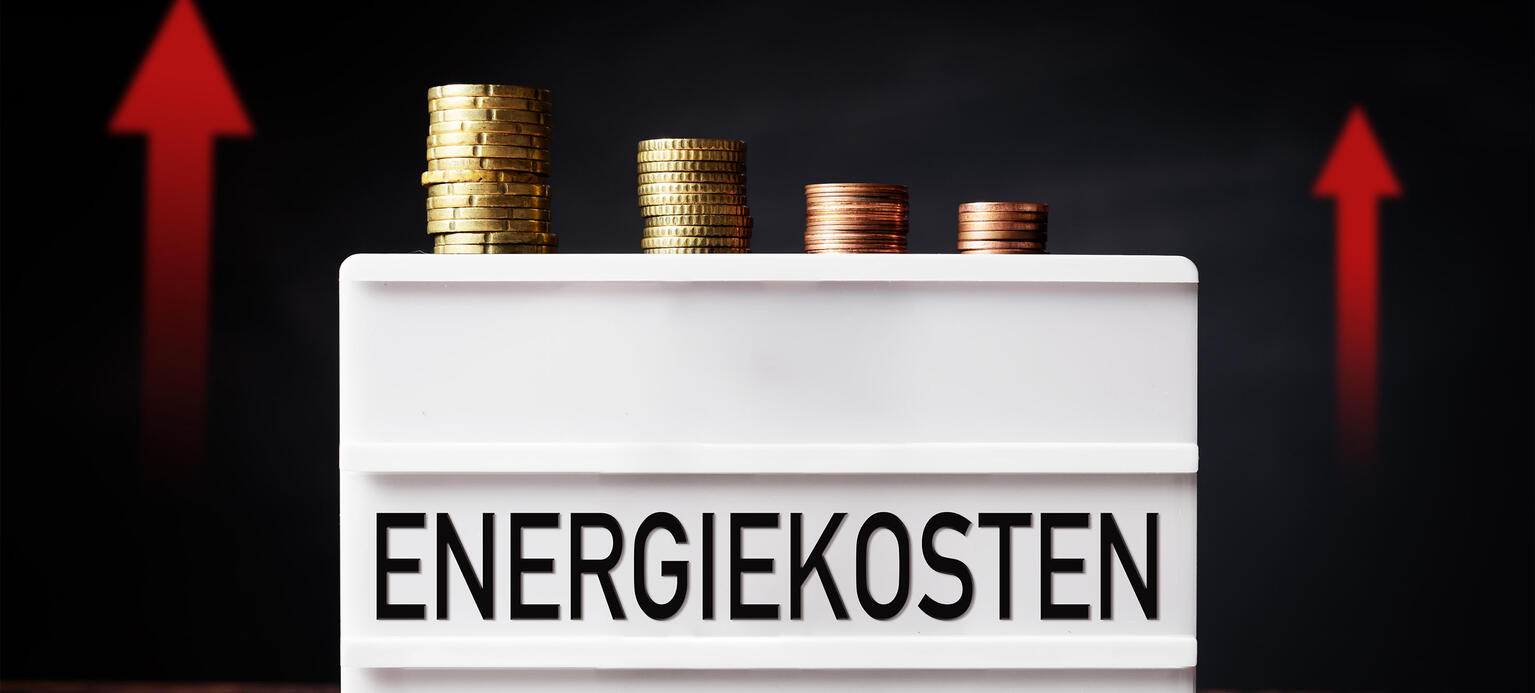 Fotomontage: Lichtbox mit Euro Münzen und der Aufschrift Energiekosten, steigende Energiepreise – Mindestlohnerhöhung  