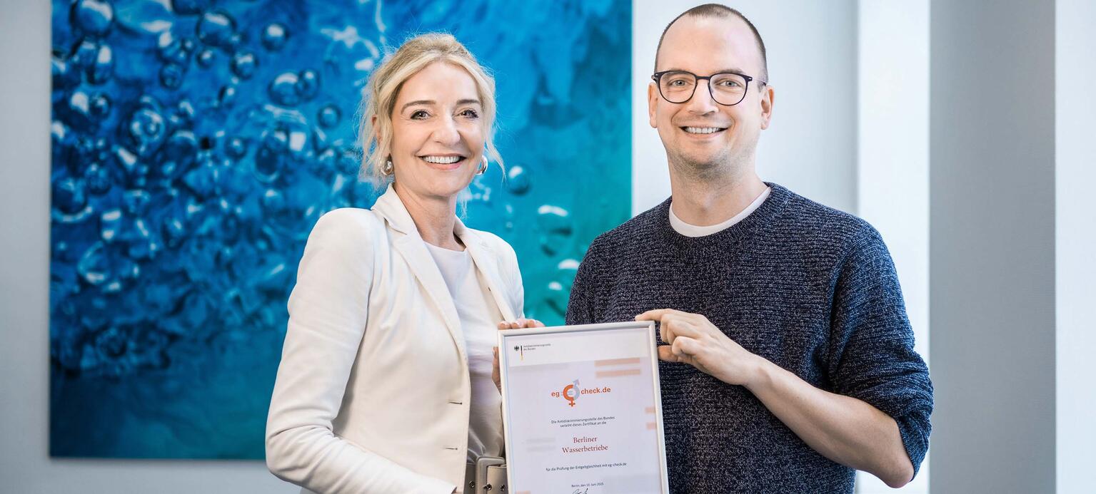 Personalvorständin Kerstin Oster (links) und der Diversity-Beauftragte Jan Pedd (rechts) von den Berliner Wasserbetrieben, gerahmtes Zertifikat des eg-Checks haltend
