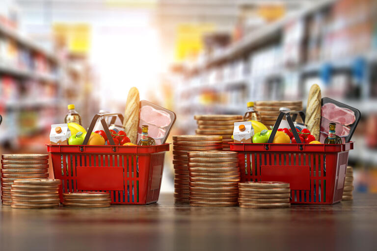 Growth of food sales or growth of market basket or consumer price index concept. Shopping basket with foods with coin stacks in grocery shop. Inflationsmonitor