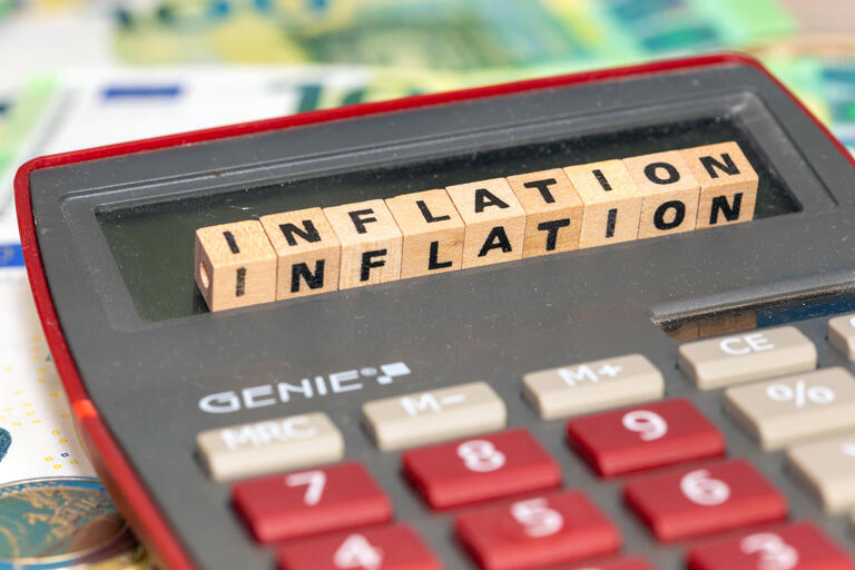 Symbolbild Inflation: Buchstabenwürfel auf einem Taschenrechner zeigen das Wort Inflation an - Inflationsmonitor