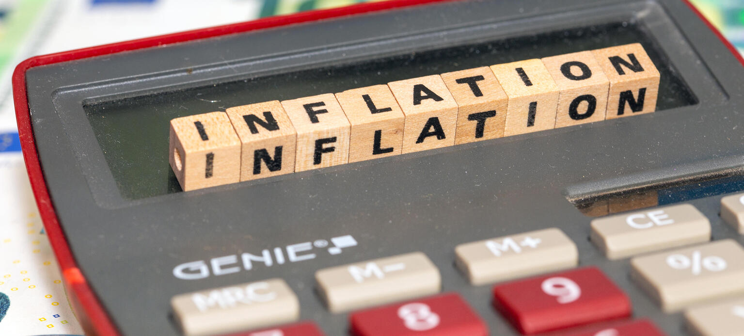 Symbolbild Inflation: Buchstabenwürfel auf einem Taschenrechner zeigen das Wort Inflation an - Inflationsmonitor
