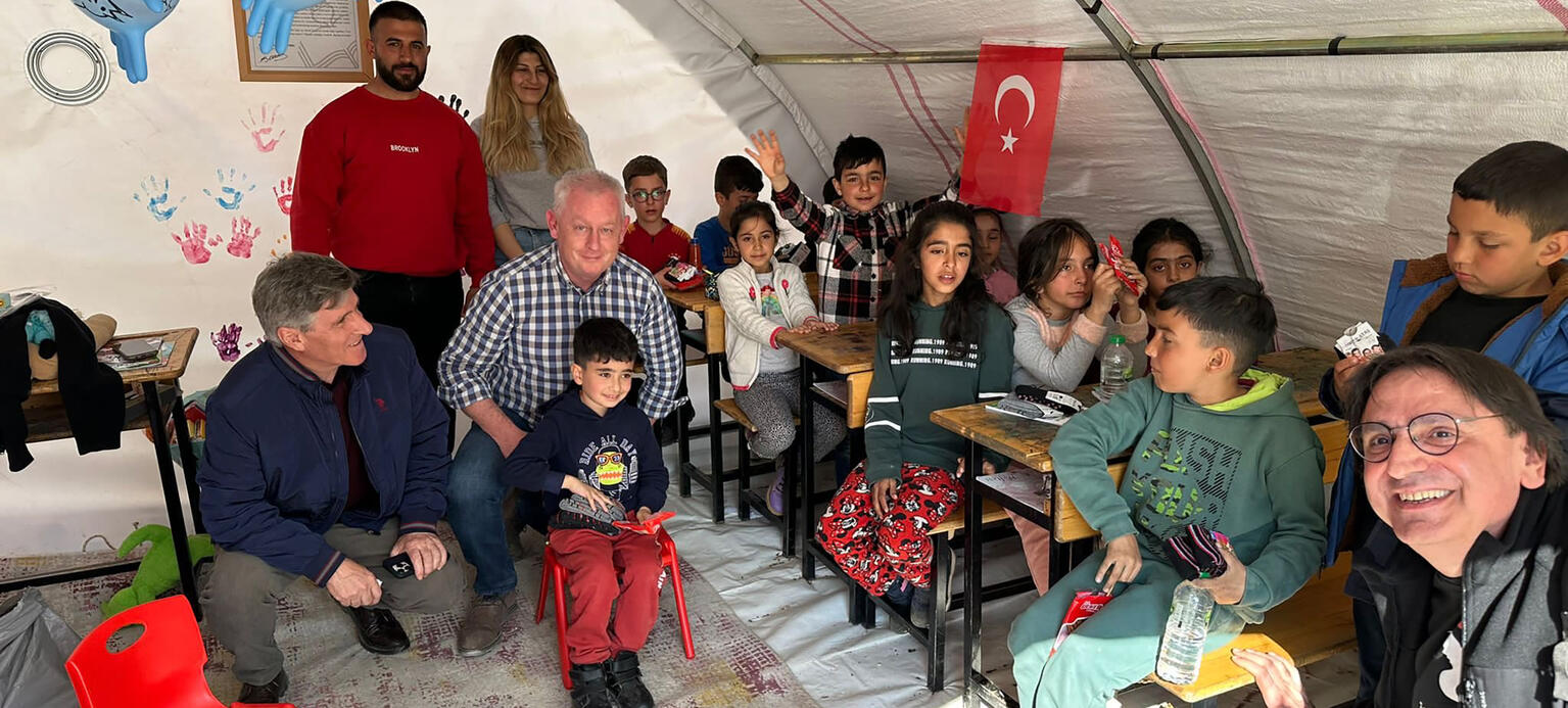 Kemal Özkan, stellvertretender Generalsekretär von IndustriALL global (vorne rechts) besucht eine provisorische Schule im Erdbebengebiet der Türkei.