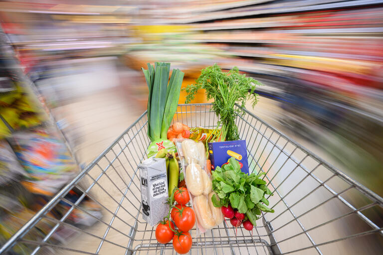  Ein mit Lebensmittel gefüllter Einkaufswagen wird durch einen Supermarkt geschoben - Inflationsmonitor