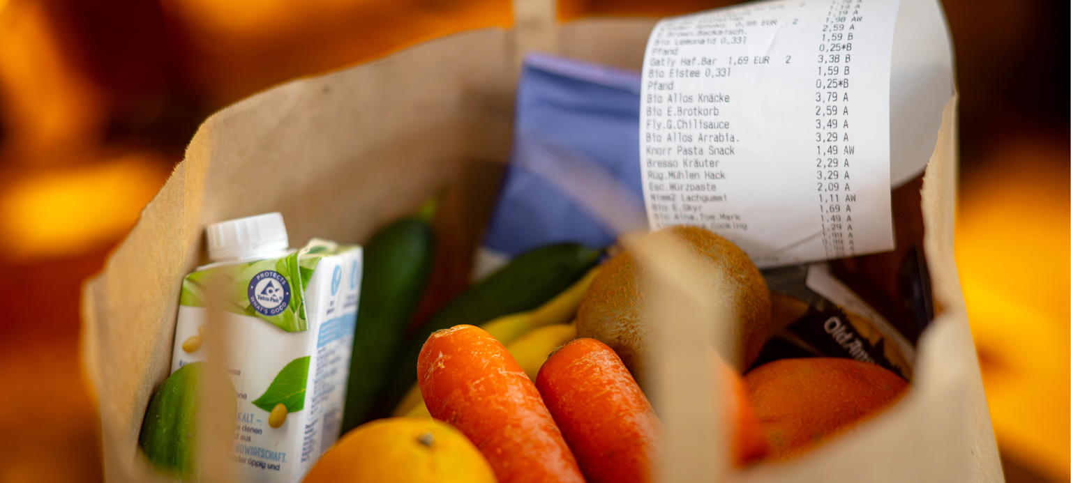 Ein Kassenbon liegt auf den Lebensmitteln in einer Einkaufstüte. 