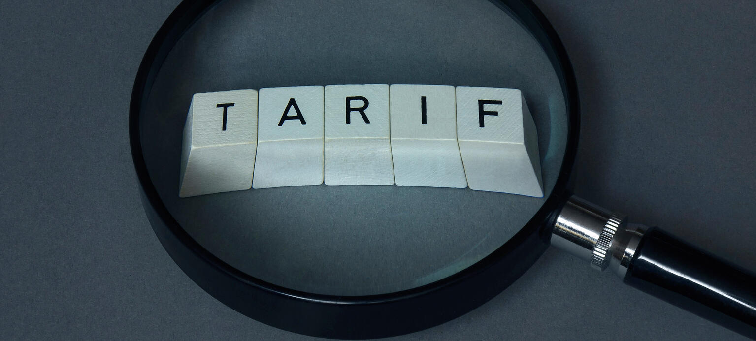 Unter einer Lupe liegen Buchstabenwuerfel mit dem Schriftzug Tarif.