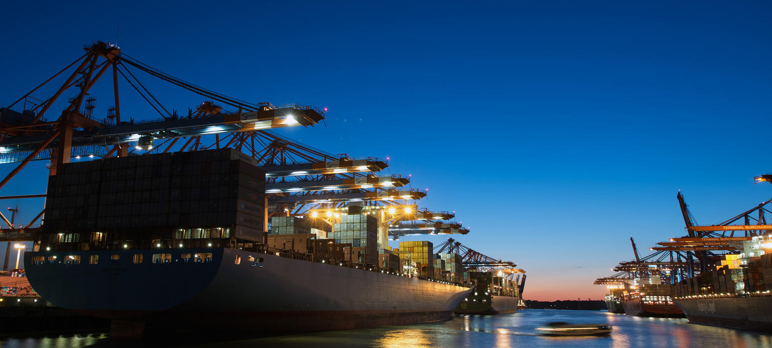 Containerschiffe liegen am während der Abenddämmerung im Hafen in Hamburg.