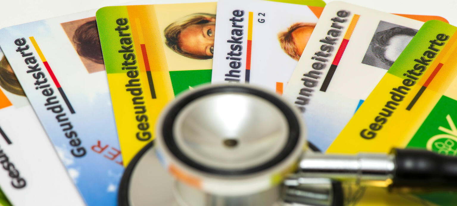 Ein Stethoskop liegt auf vielen Gesundheitskarten verschiedener Krankenkassen.