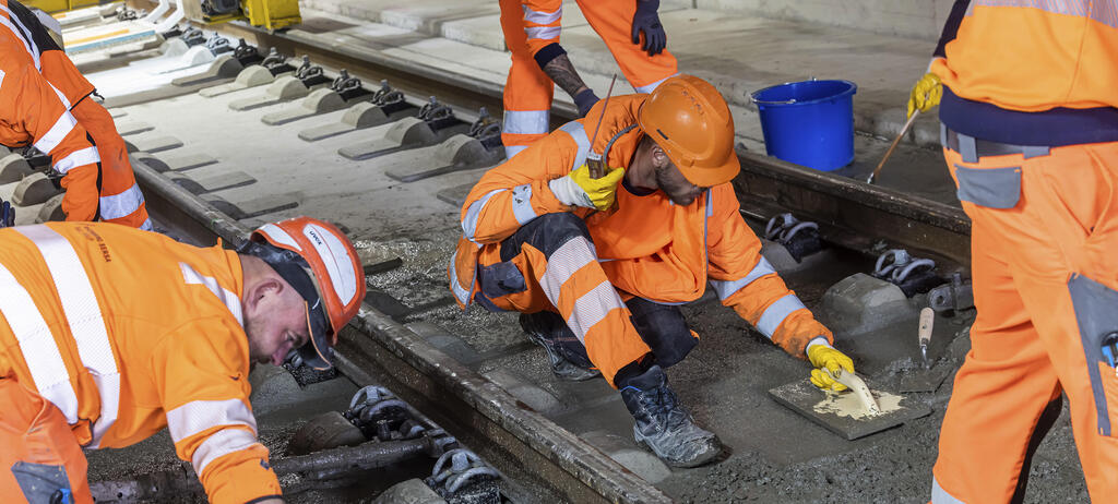 Arbeiter verlegen  Schienen für die Deutsche Bahn und betonieren das Gleisbett. 