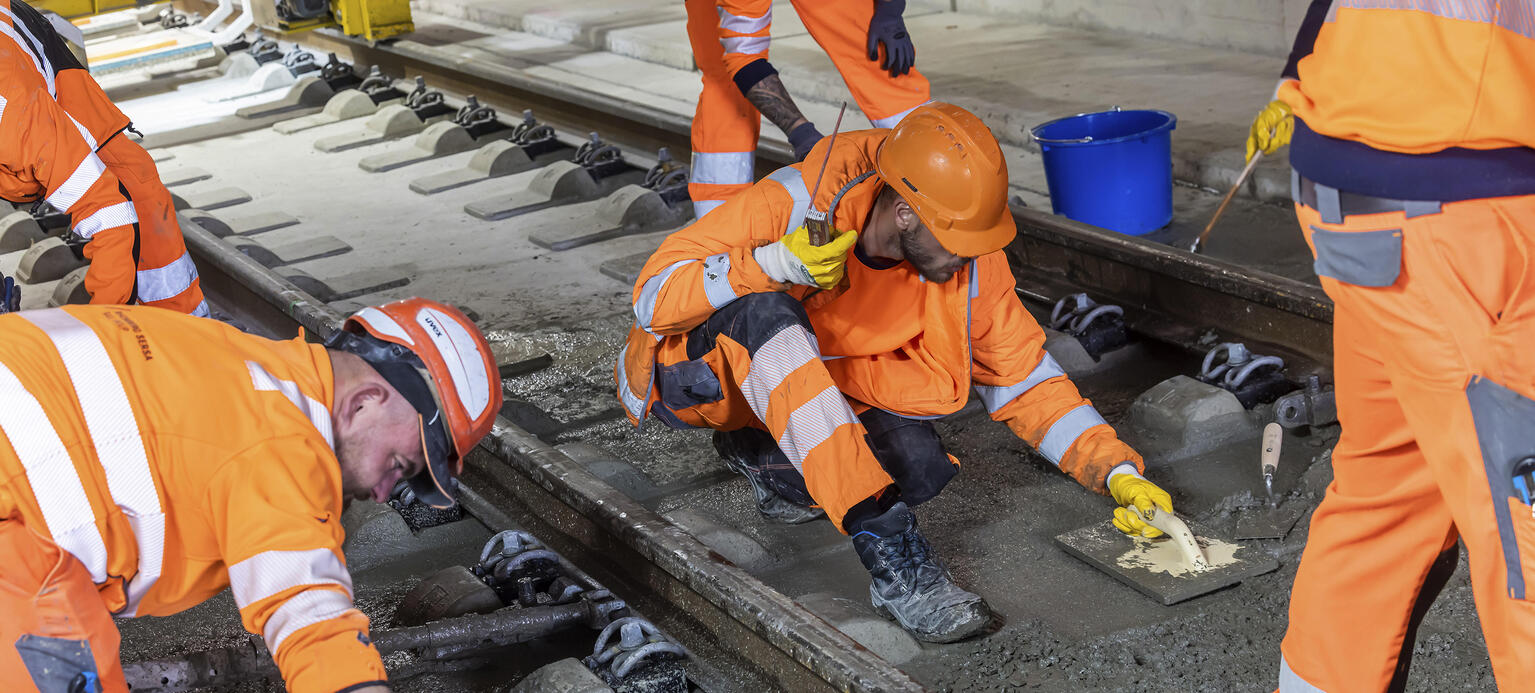 Arbeiter verlegen  Schienen für die Deutsche Bahn und betonieren das Gleisbett. 