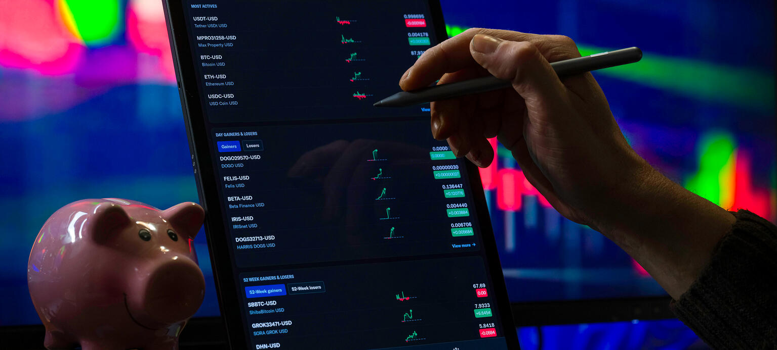 Symbolbild: Auf einem Tablet sind Aktienkurse zu sehen. Daneben steht ein Sparschwein.