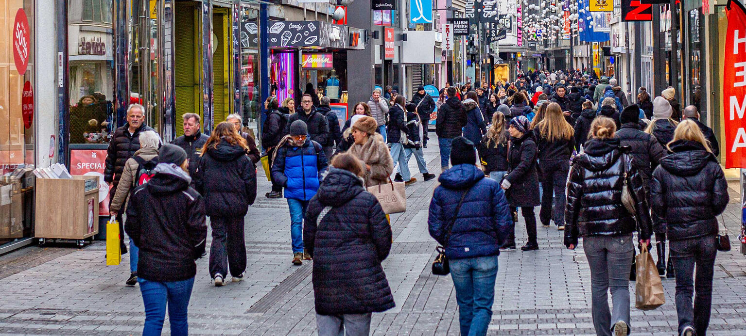 Menschen sind auf einer Einkaufsstraße unterwegs.