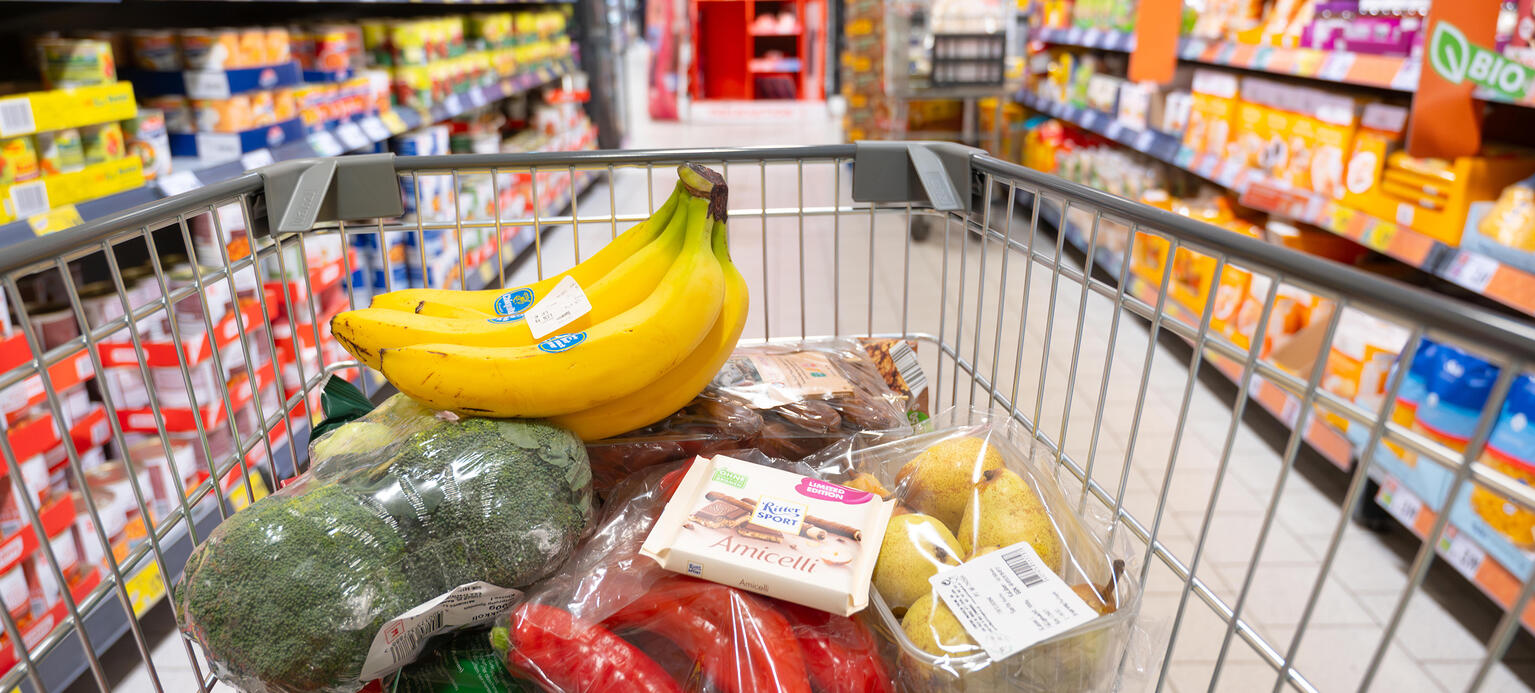 Frisches Gemüse, Obst und Schokolade, Einkaufswagen mit Lebensmitteln in einem Supermarkt.