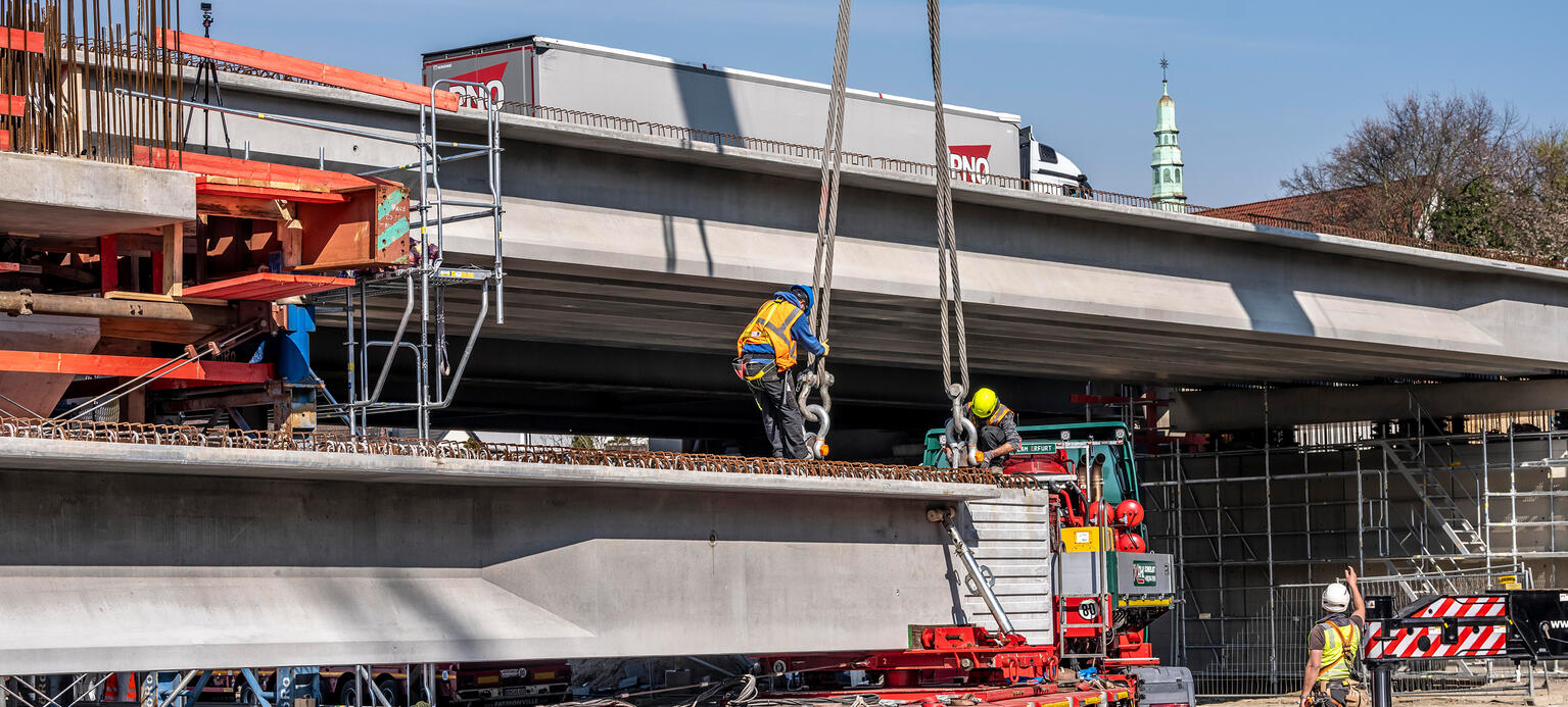 Ein Teil einer neuen Brück wird mit einem LKW transportiert und steht vor der entsprechenden Baustelle.
