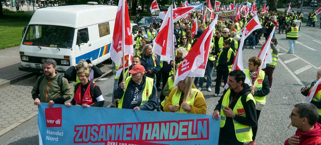 Verdi Gewerkschaftsmitglieder gehen mit rot-weissen Fahnen und Plakaten auf die Strasse.