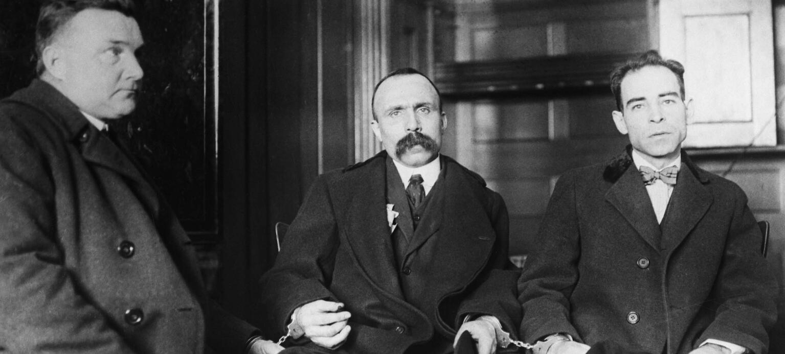 Historische SW-Aufnahme von Nicola Sacco (rechts) und Bartolomeo Vanzetti (Mitte) auf einer Bank im Gerichtsgebäude der US-Stadt Dedham in Massachusetts
