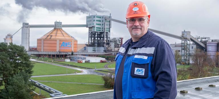 Betriebsratsvorsitzender Oliver Elsen in Arbeitskleidung mit Helm vor dem Werksgelände von AOS Stade