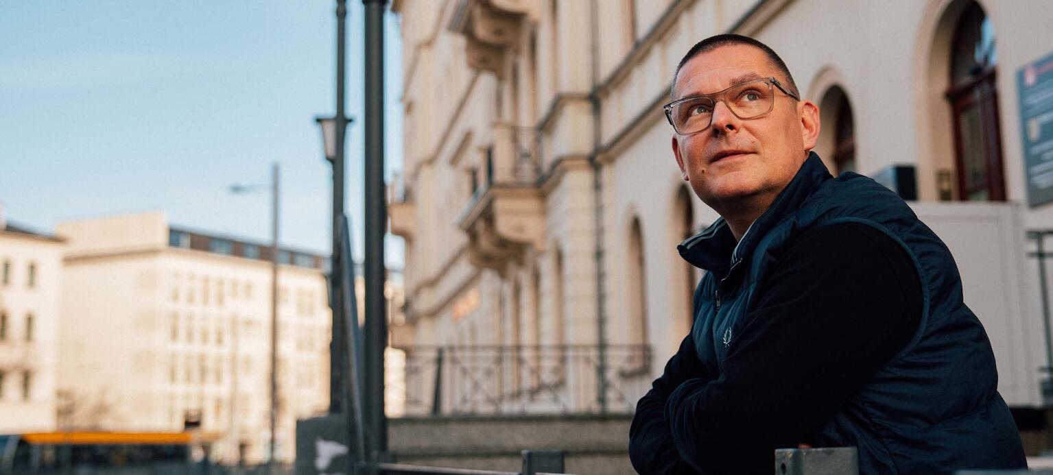 Porträtfoto von Sebastian Reissig mit Gebäude im Hintergrund