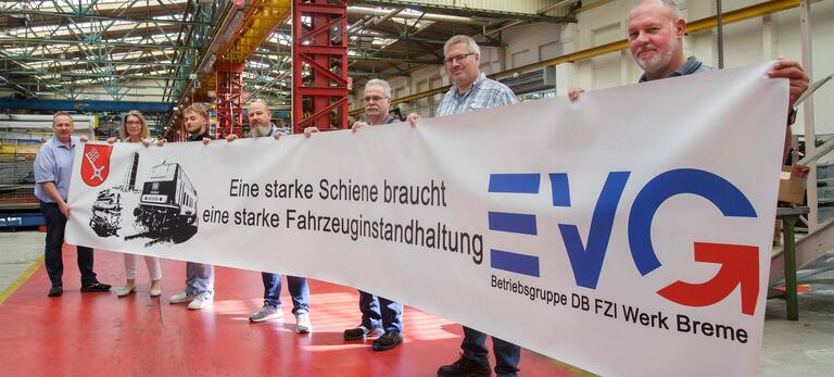 Betriebsrat der DB-Fahrzeuginstandhaltung in Bremen in Werkshalle mit einem Banner für den Erhalt der Fahrzeuginstandhaltung