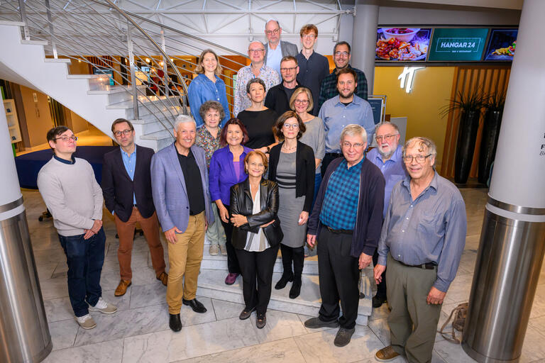 Eine Gruppe von Wissenschaftler*innen stehen vor einem Treppenaufgang und werden fotografiert