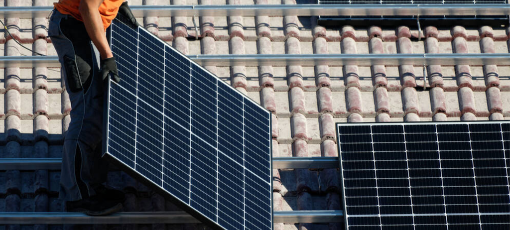 Ein Arbeiter legt Solarpanele auf ein Dach