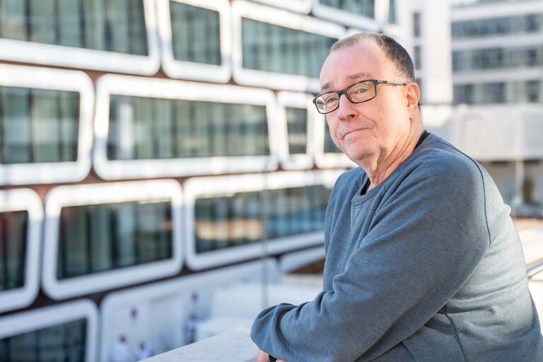 Klaus Röllecke, Betriebsratsvorsitzender blickt über ein Geländer auf ein Gebäude der DZ Bank