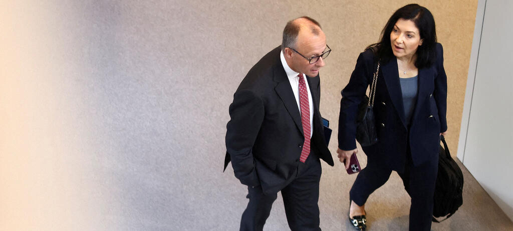 Bundeskanzler Merz (li.) und  Wirtschaftsministerin Reiche (re.) gehen nebeneinander über einen Gang  im Bundestag