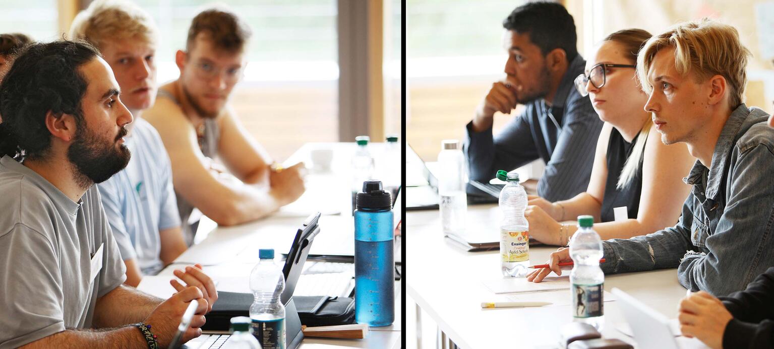 Teilnehmende der Sommerakademie sitzen sich beim Planspiel zu Tarifverhandlungen an langen Tischen gegenüber.