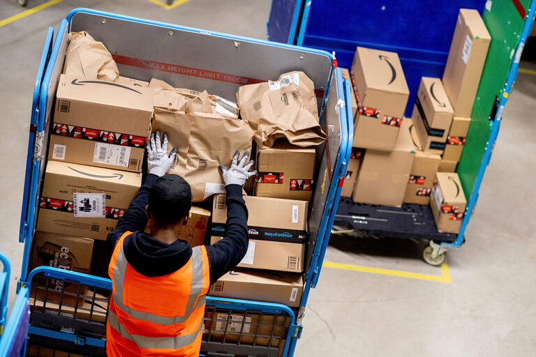 Mitarbeiter im Logistikzentrum von Amazon beim Verladen von Paketen